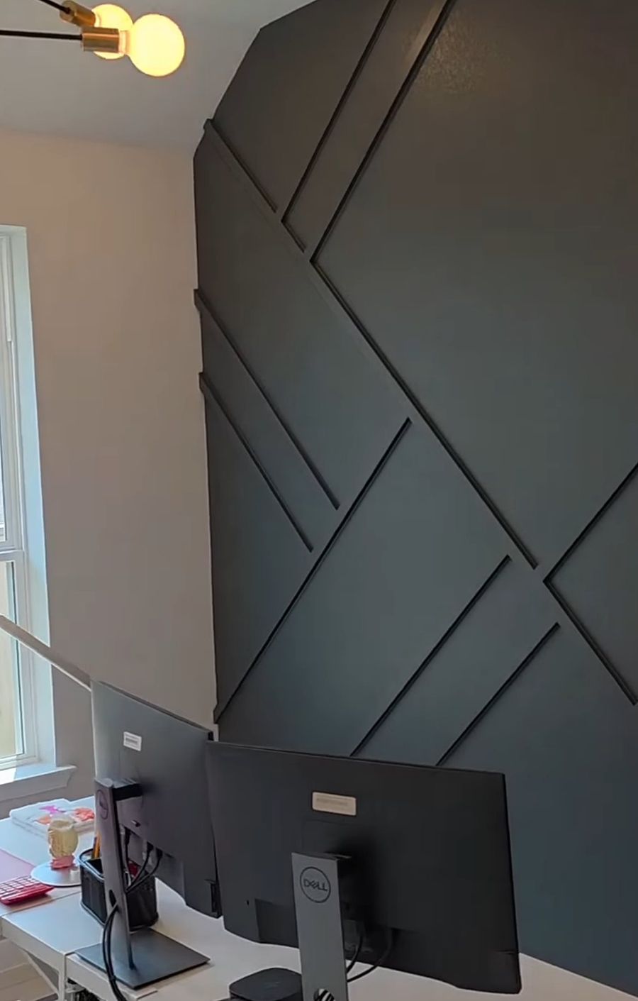 Dark geometric accent wall made of crossing trim in a home office